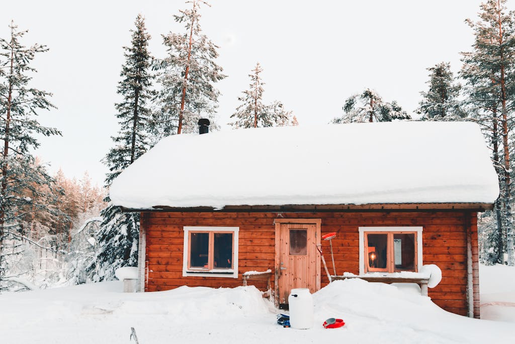 Experience the serene beauty of a snow-covered wooden cabin amidst the Finnish woods during winter.