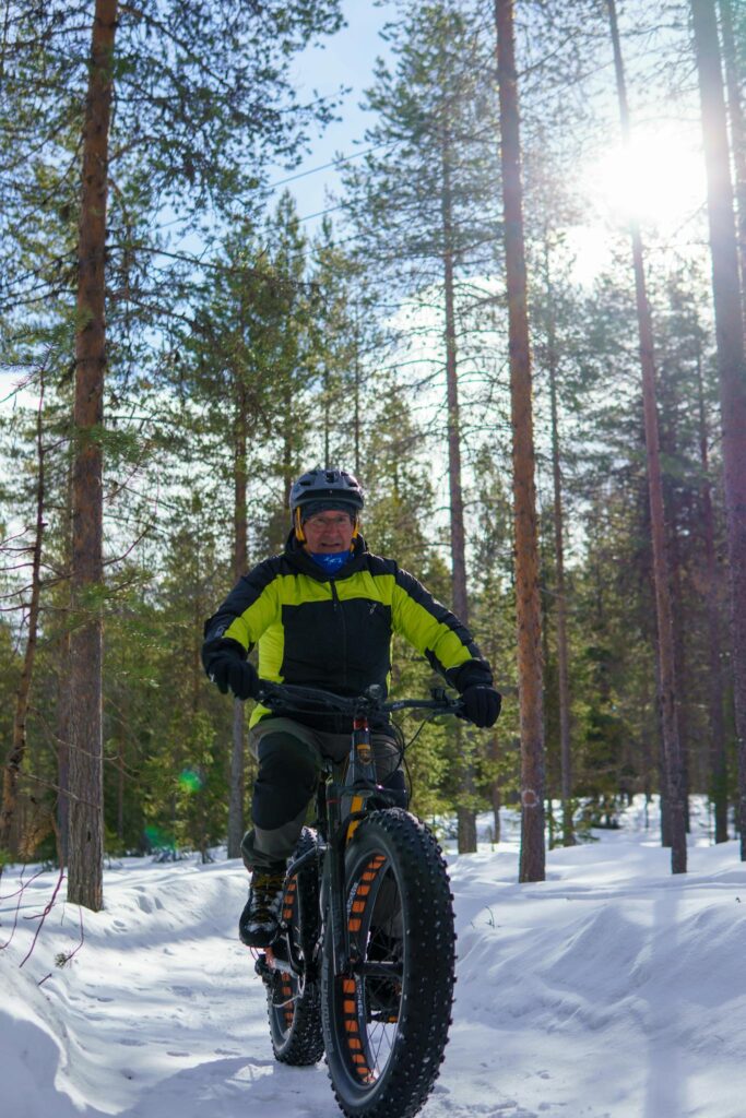 Explore winter cycling through snowy Lapland woods on a fat tire electric bike during a sunny day.