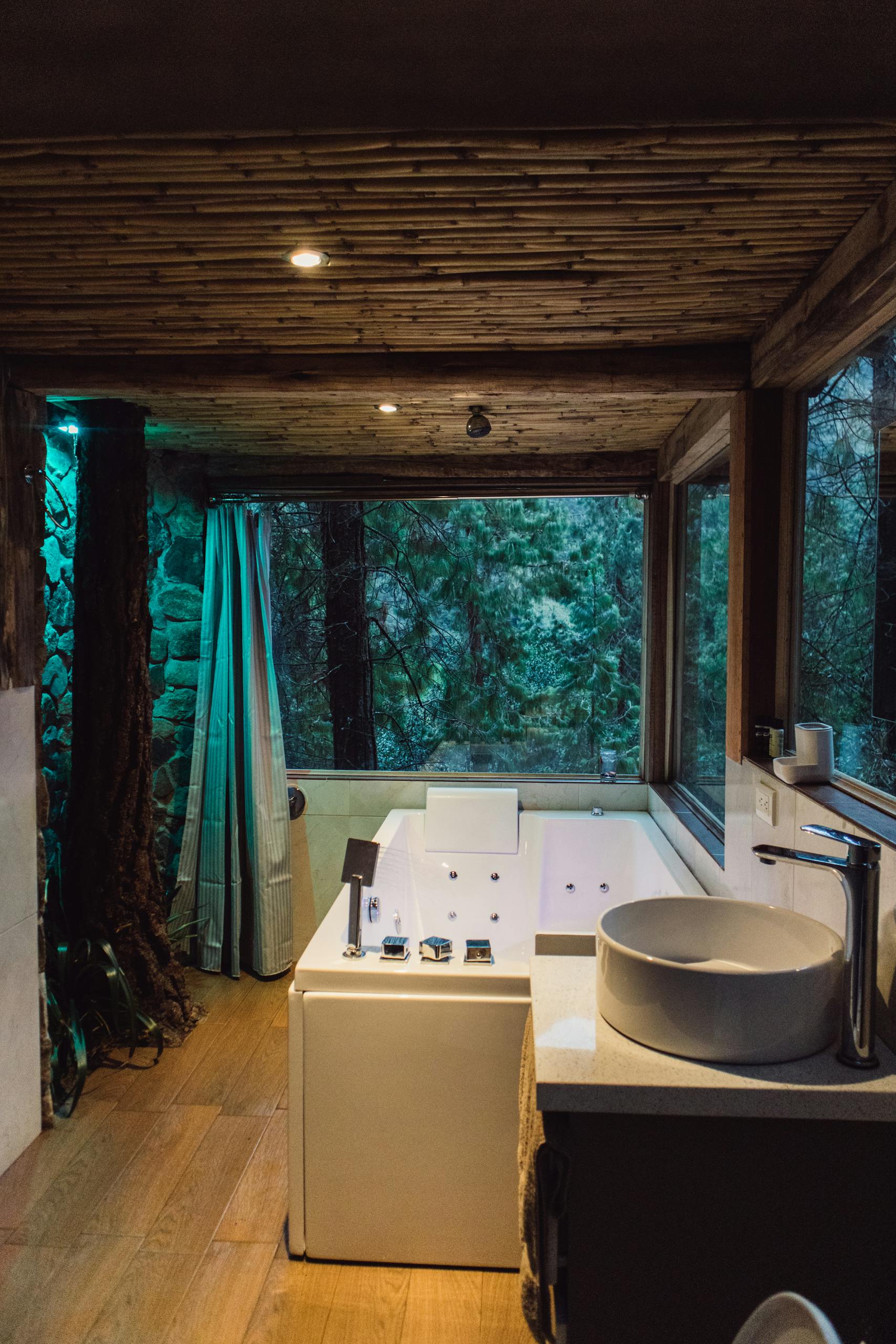 Luxurious indoor spa bathroom with modern design amidst a tranquil forest view.
