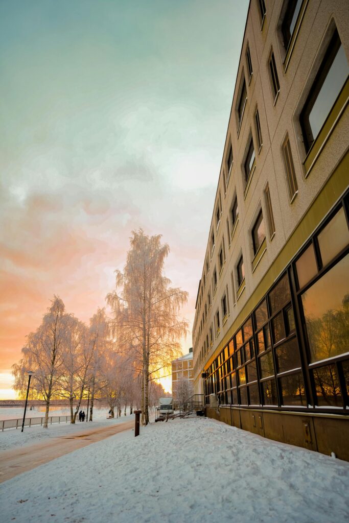 Snow-covered landscape with sunset reflections on a building in Rovaniemi, Finland.