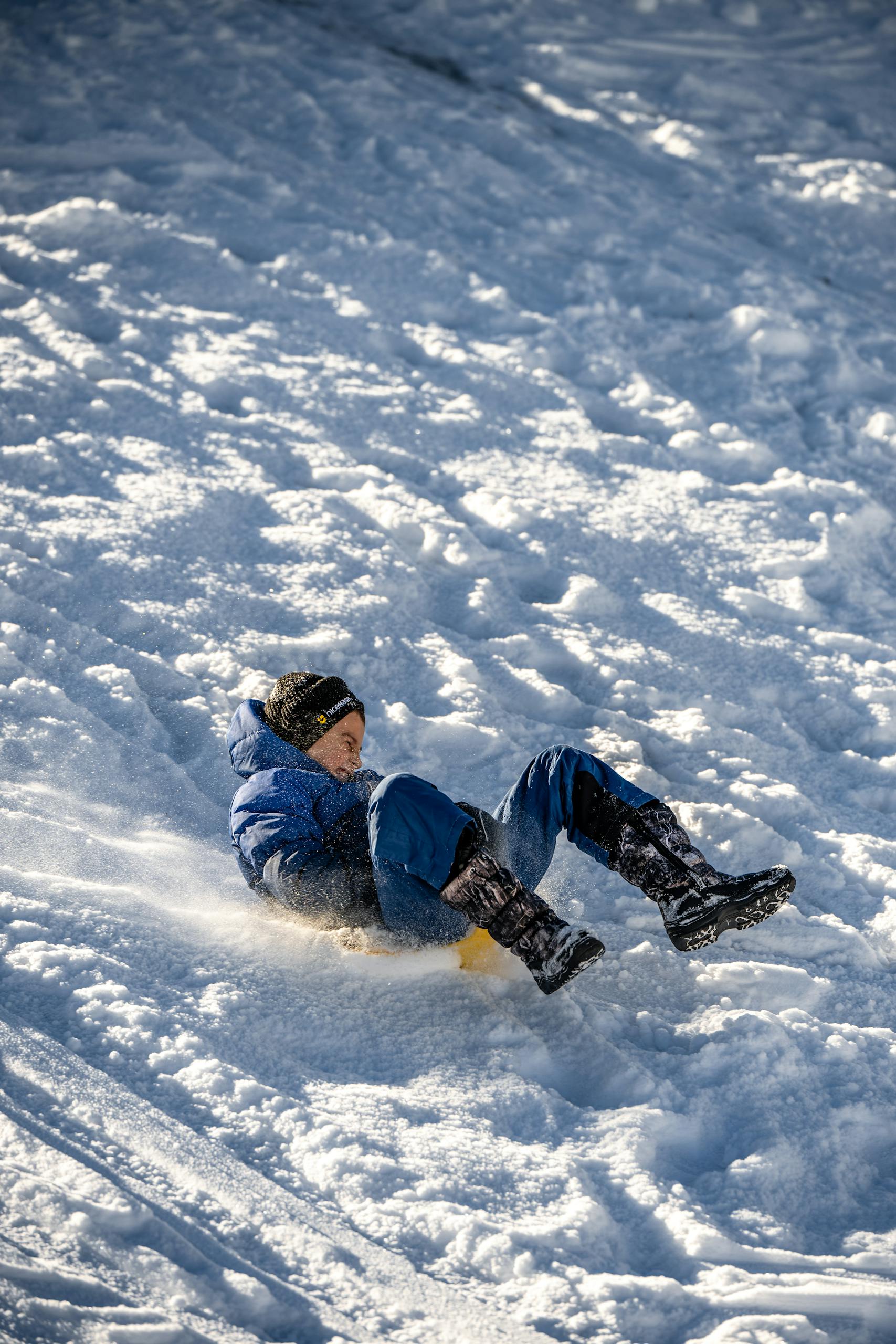 Young boy enjoying winter sledding on a snowy hill in lapland